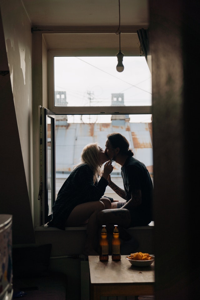 A Couple Kissing while Sitting on the Windowsill